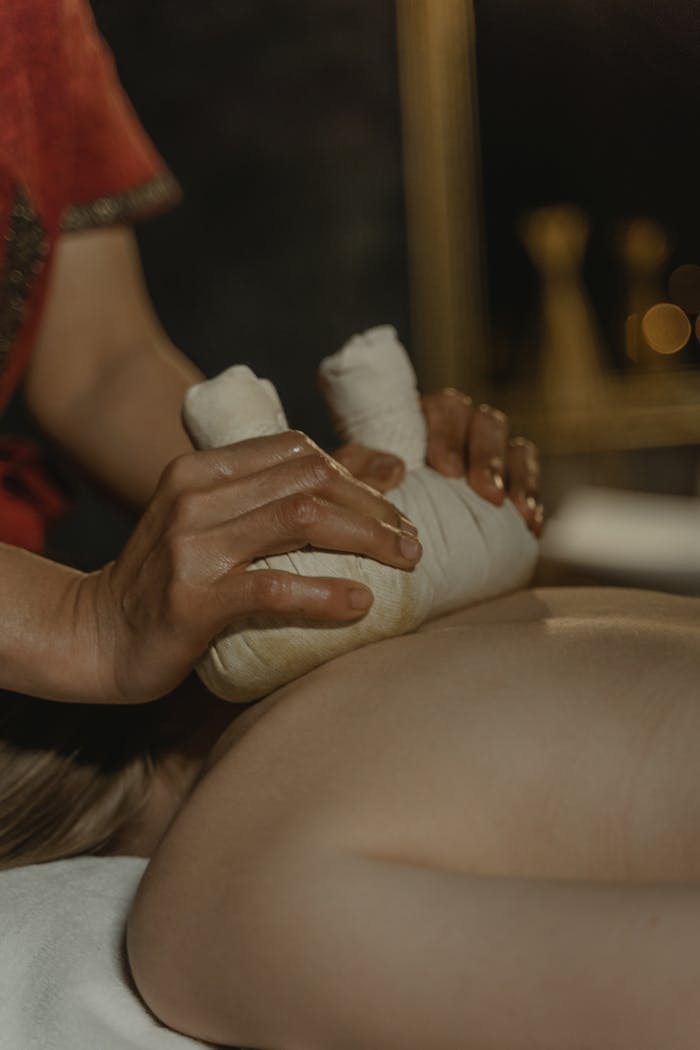 Close-up of a woman receiving a relaxing herbal massage therapy session with selective focus.